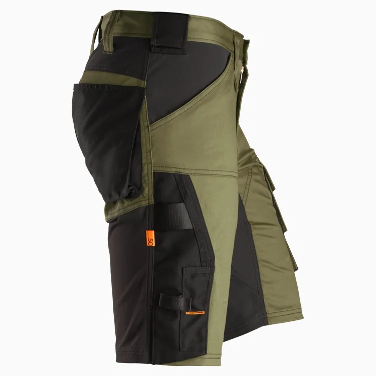 Side view of olive green and black tactical shorts with multiple cargo pockets and orange accent tags, showing rugged utility design.